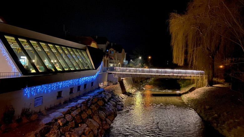 Night scene with illuminated modern building and river.