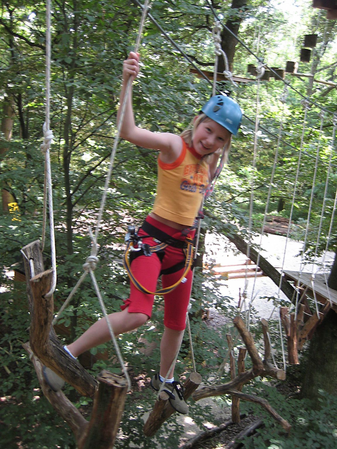 Child with helmet in the climbing park on a rope course.