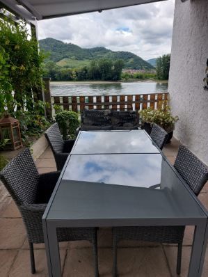 Terrace with table and chairs, view of the river and hills.
