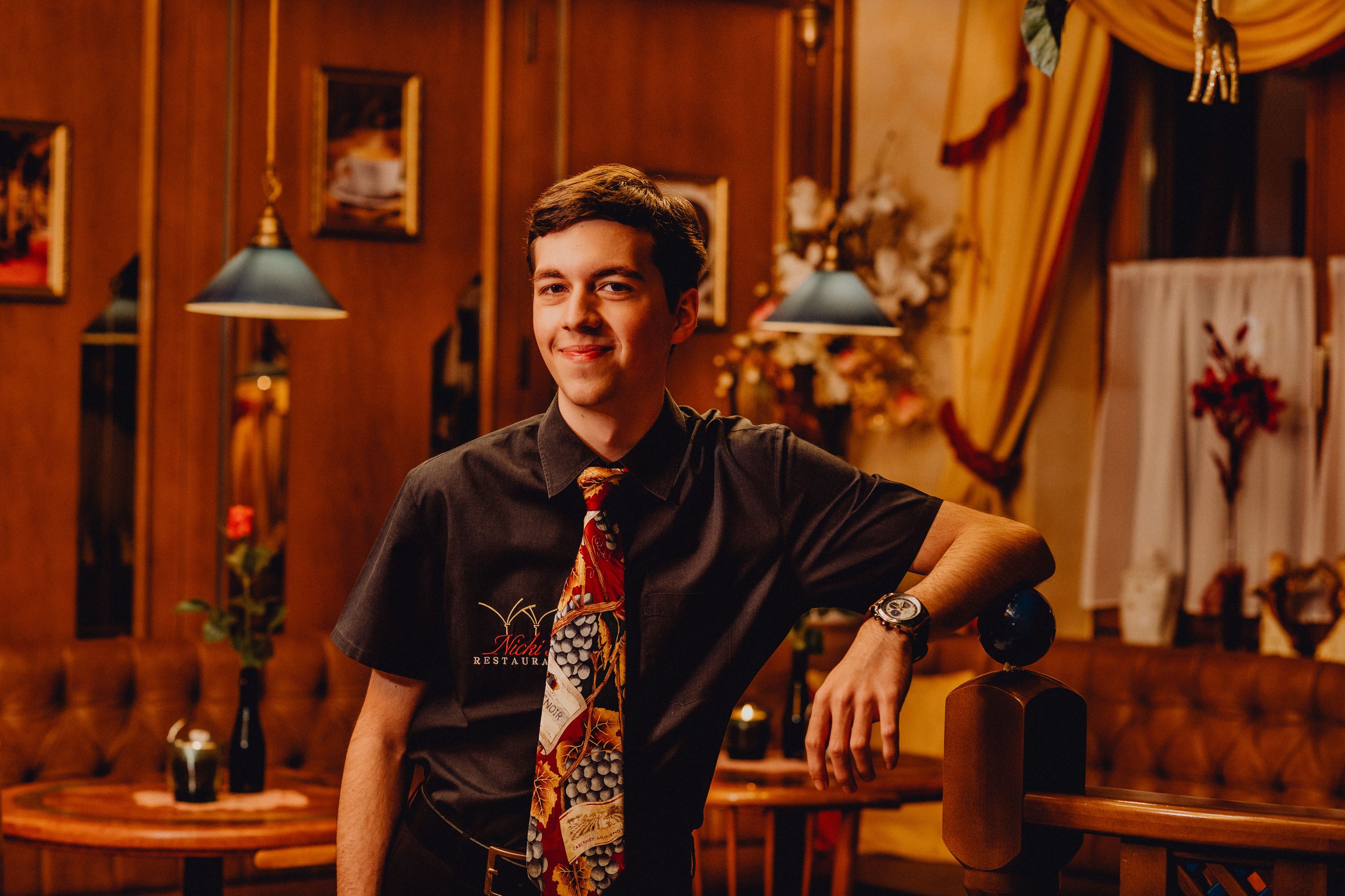 Young man in a restaurant with tie and shirt, smiling.