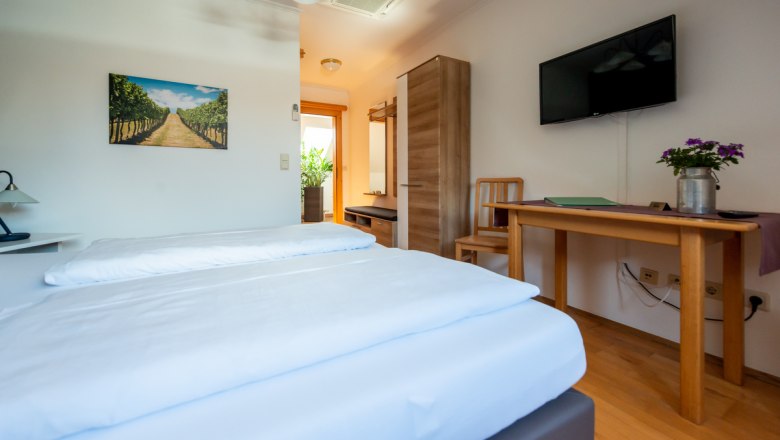Comfortable hotel room with double bed, wooden furniture, TV and plants.
