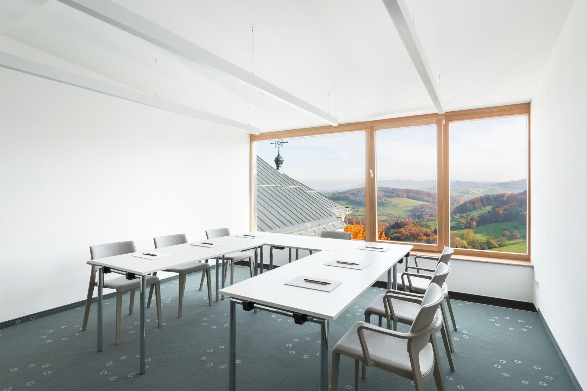 Seminar room with tables and chairs, large window overlooking the countryside.