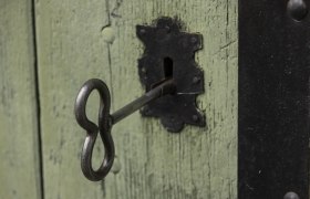 Close-up of an old key in a green wooden door lock.