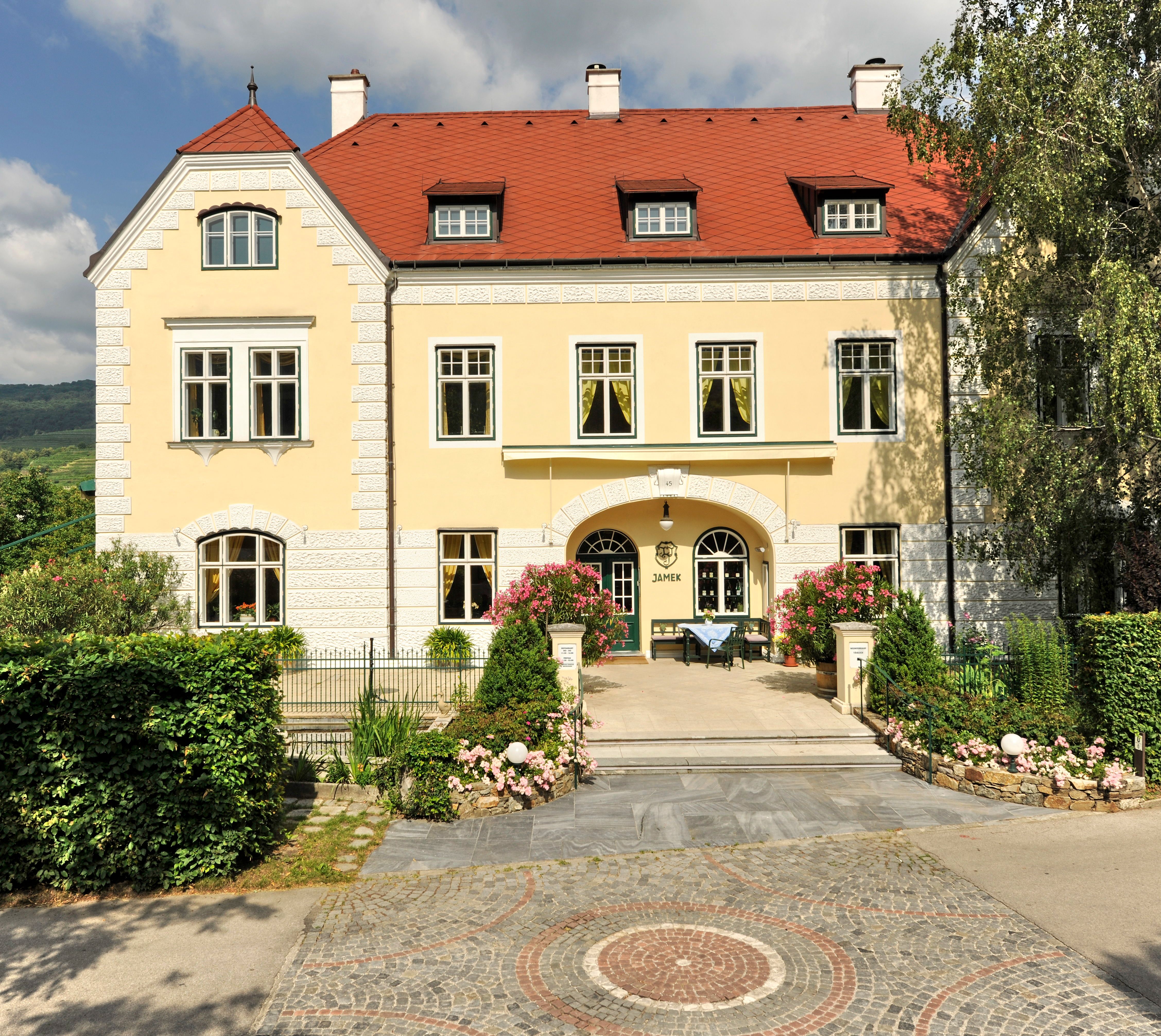 Yellow building with red roof and garden, Josef Jamek winery.