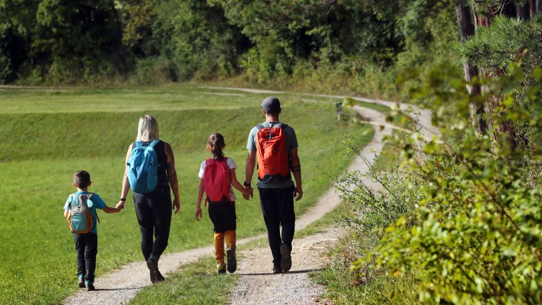 A family walks along a path through a green landscape.