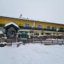 Yellow building in the snow with green veranda and entrance.