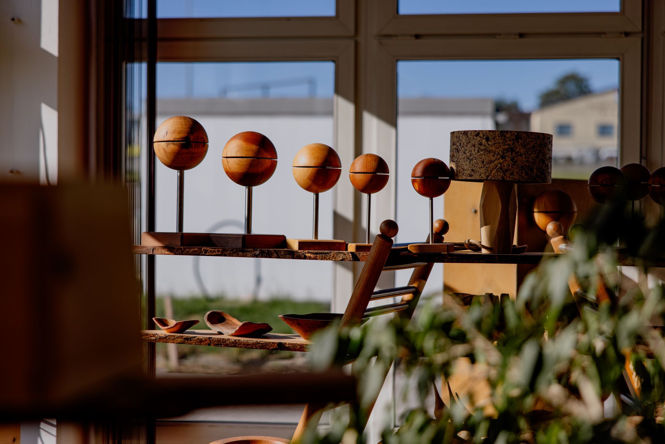 Wooden works of art in a sunny room with windows.