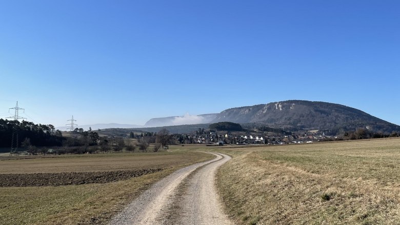 Landscape with dirt road, mountains and blue sky.