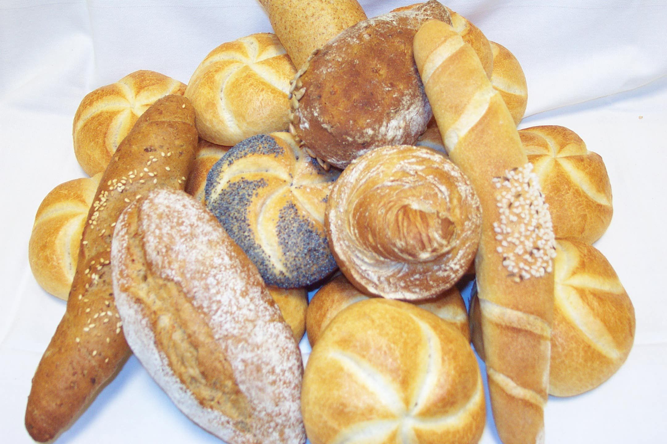 Various rolls and breads arranged on a white cloth.