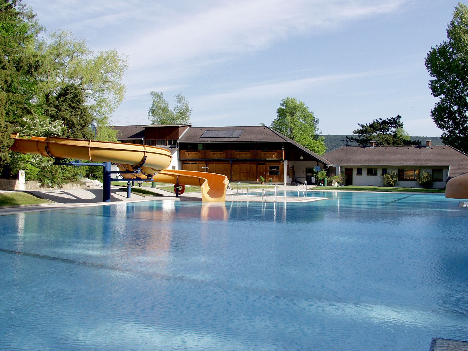 An outdoor pool with slide and buildings in the background.