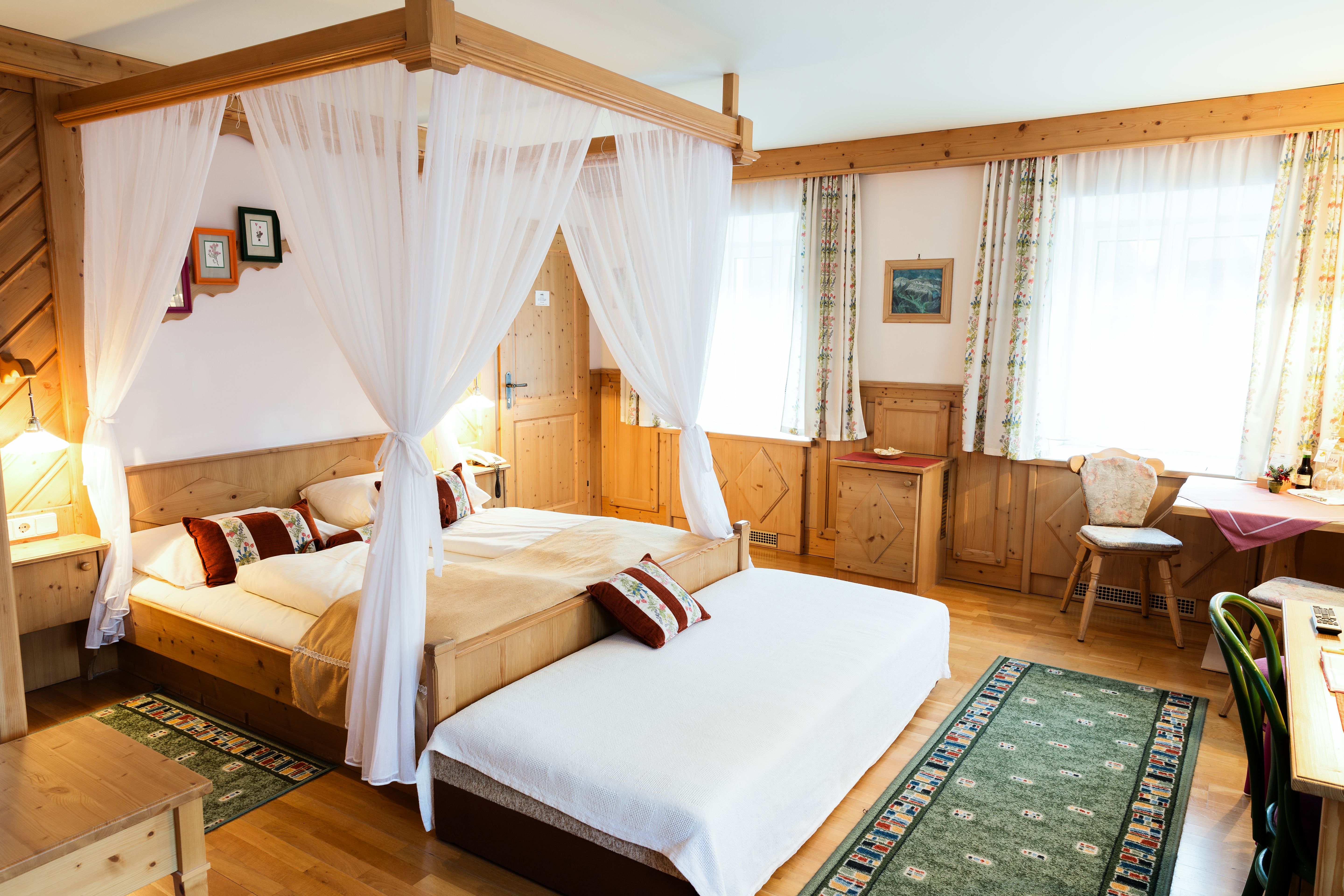 Cozy hotel room with four-poster bed, wooden furniture and carpets.