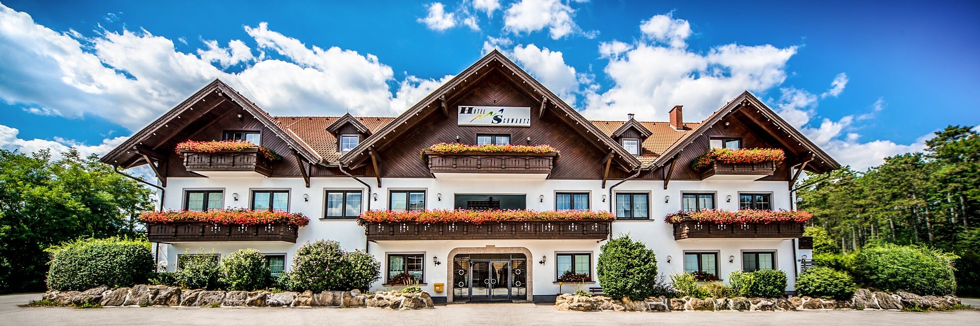 A traditional hotel with wooden balconies and flower boxes against a blue sky.