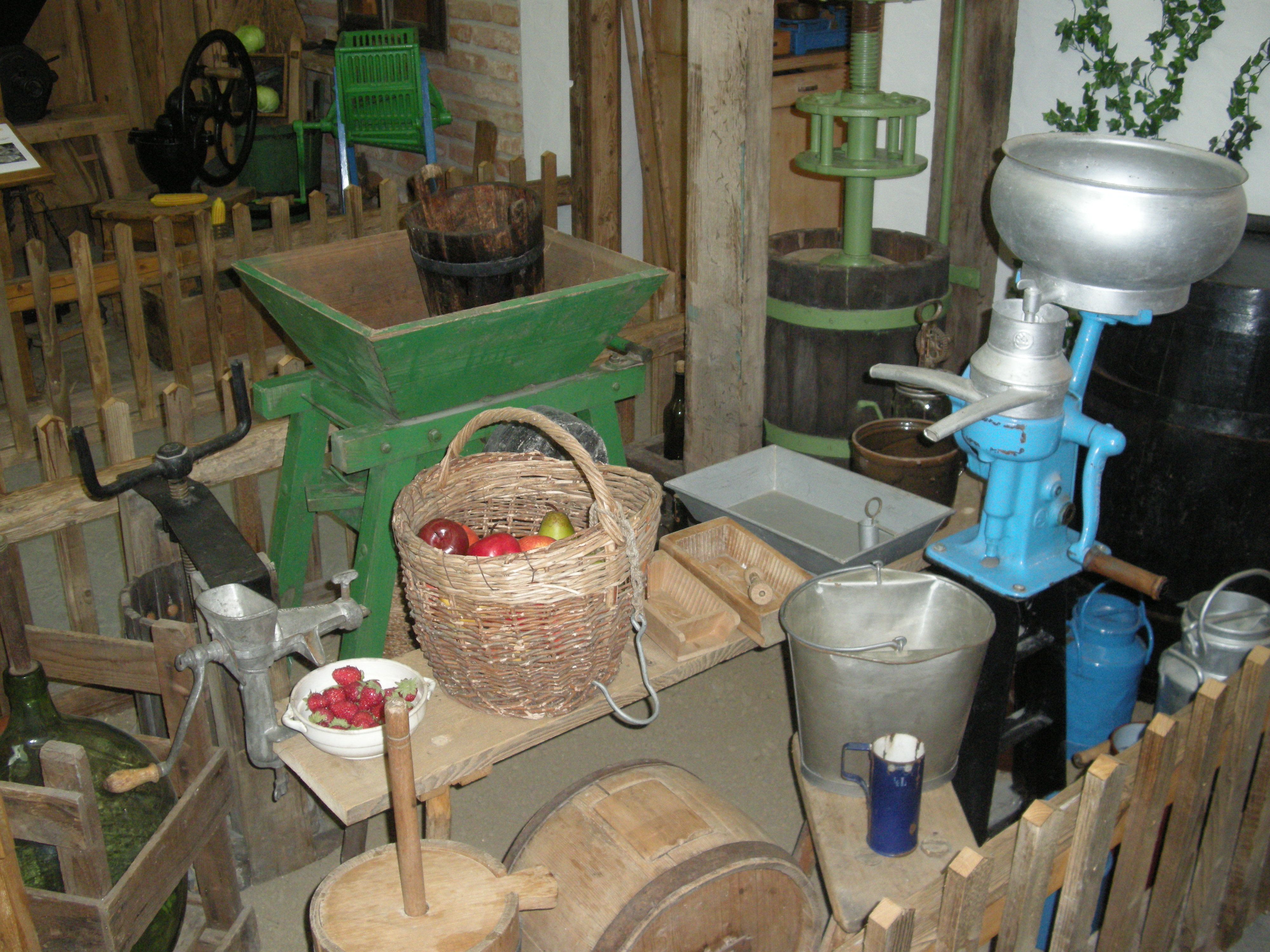 Old agricultural tools and a basket of fruit in a museum.