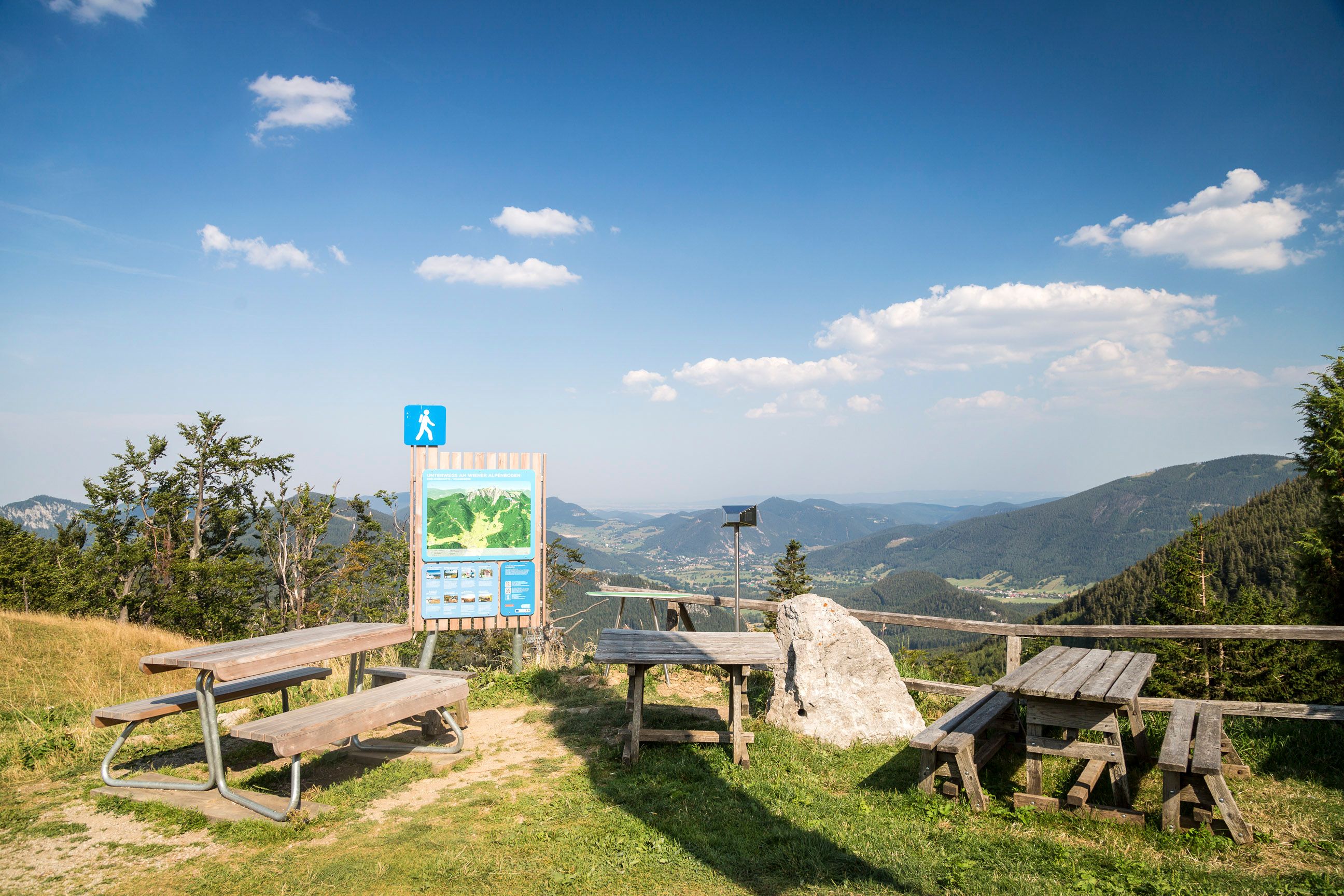 Viewpoint with wooden benches and information board in the mountains.