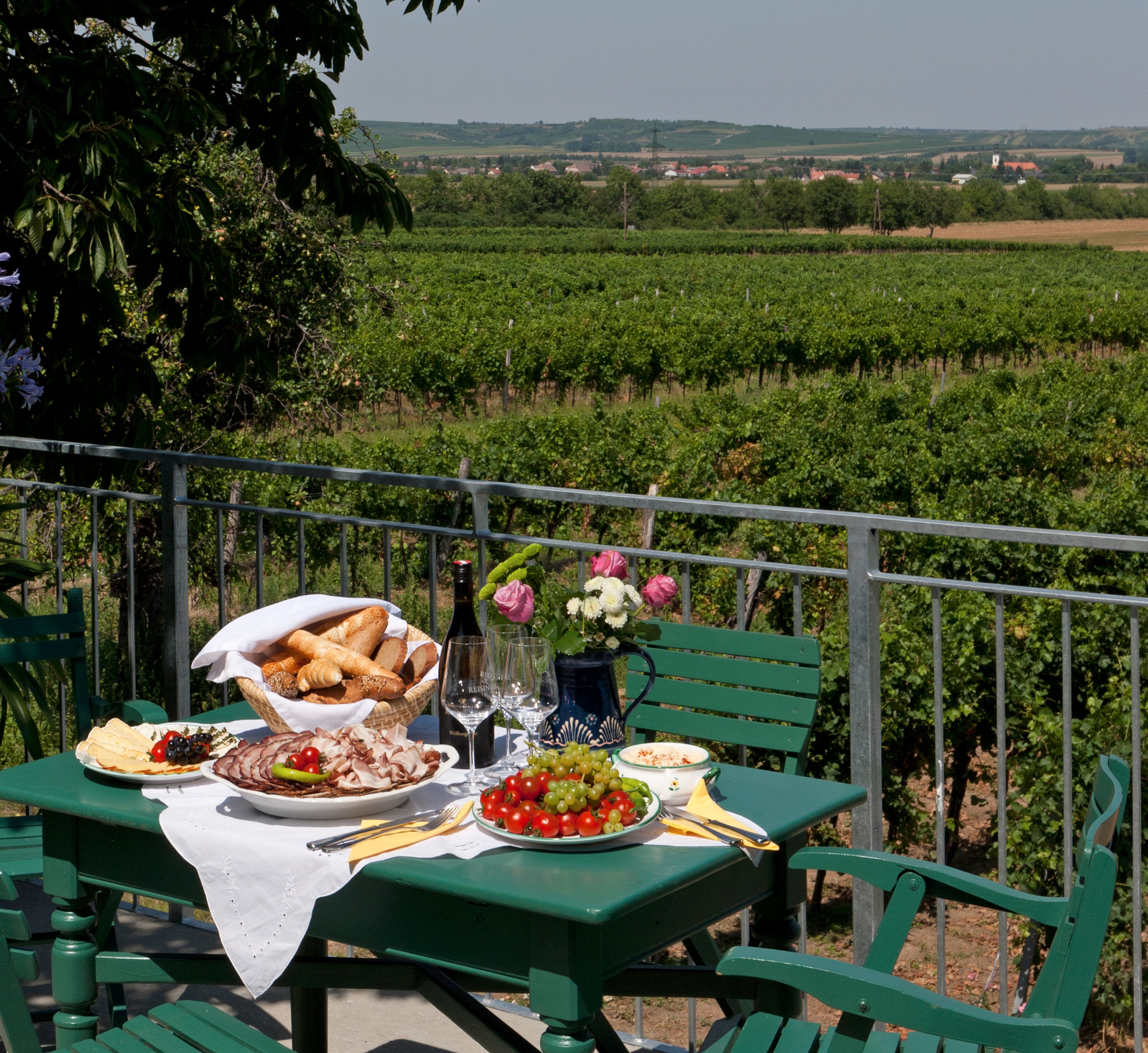 A laid table on a terrace with a view of vineyards.