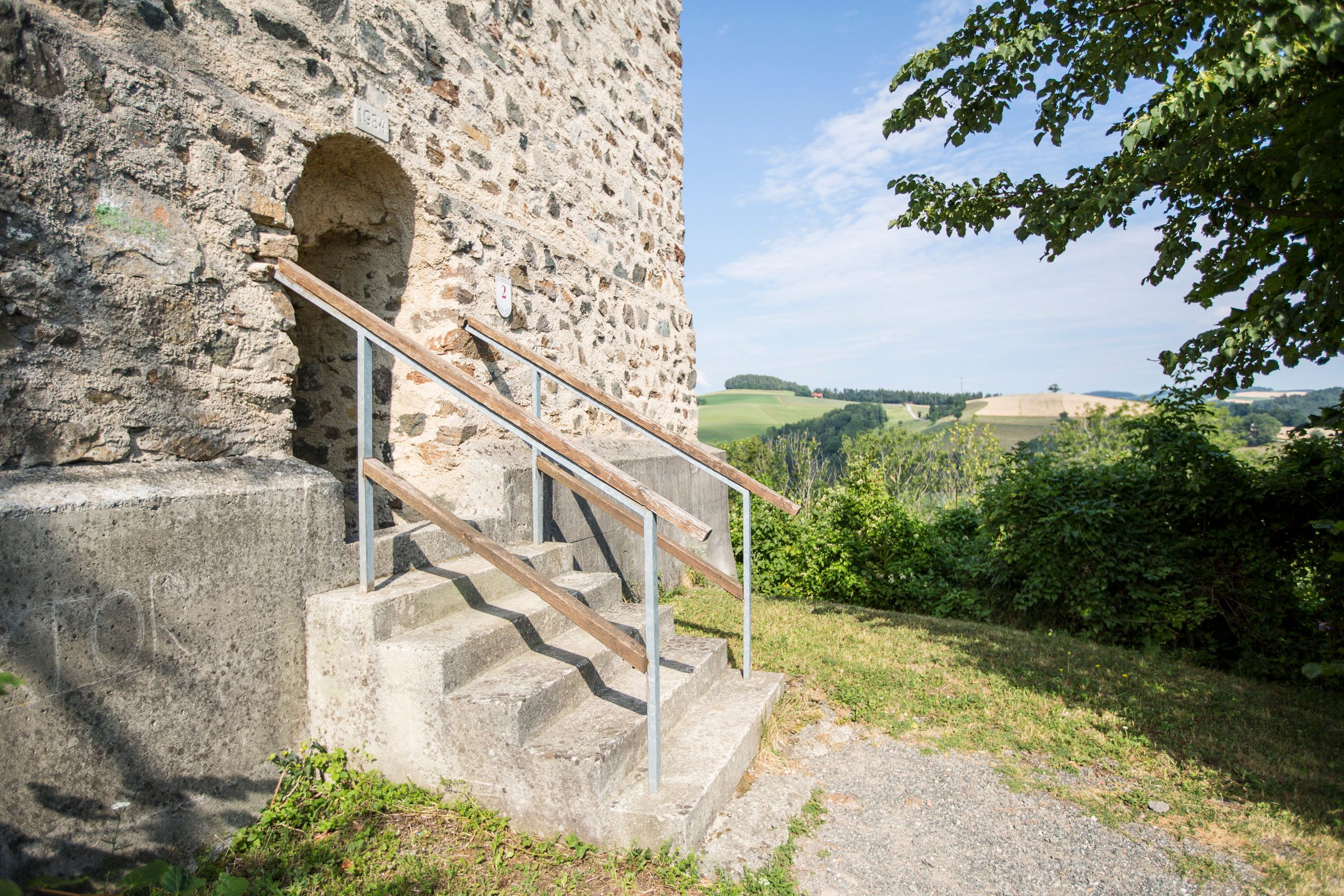 Entrance to the fire tower of the Kirchschlag castle ruins with stairs and landscape in the background.