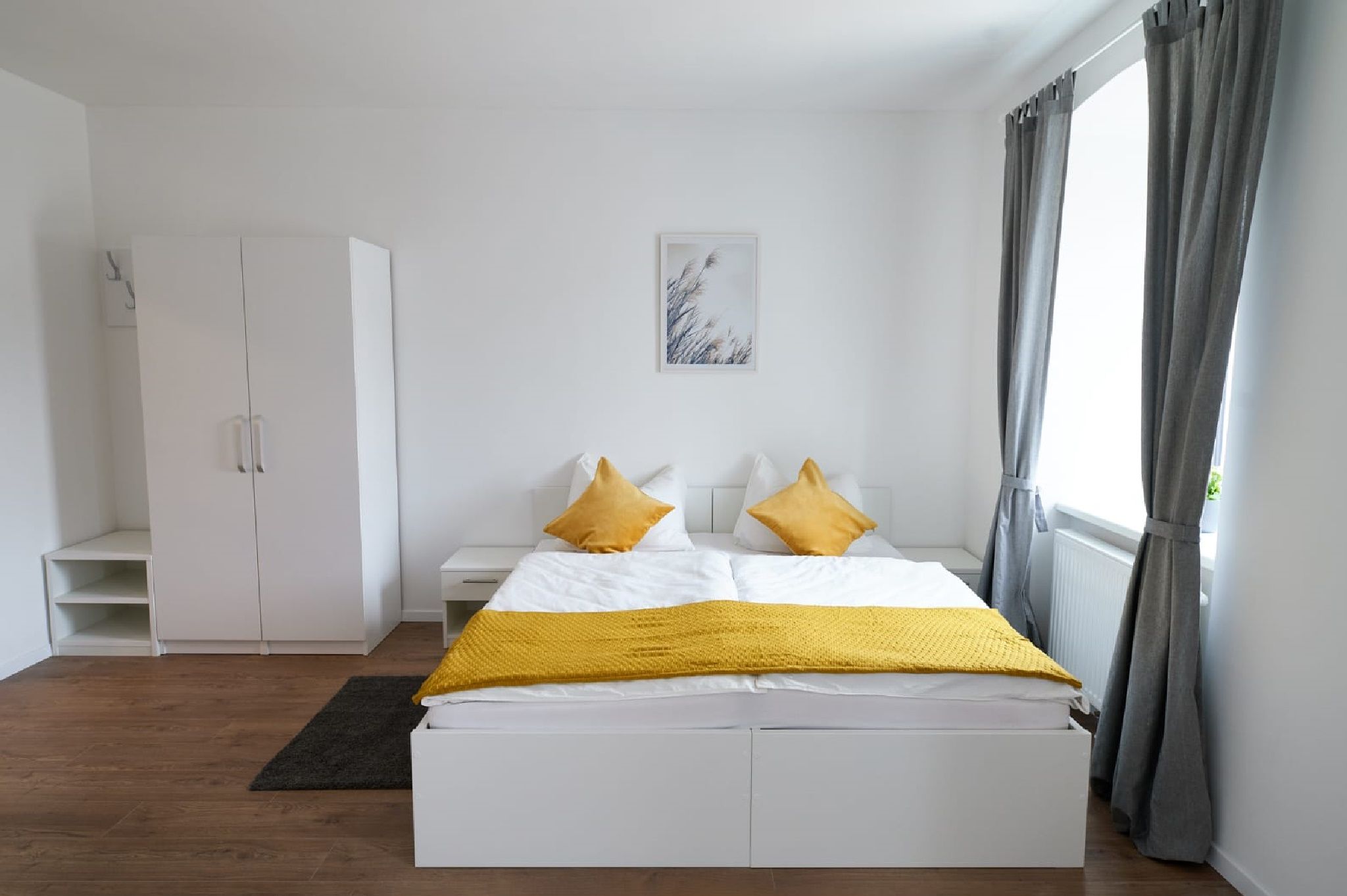 Modern double room with white bed, yellow pillows and gray curtains.