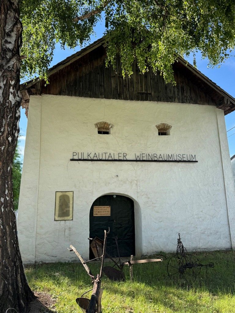 Entrance to the Pulkautal Wine Museum with old agricultural equipment in front of it.