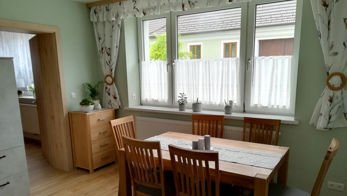 Dining room with wooden table, chairs and plants on the windowsill.