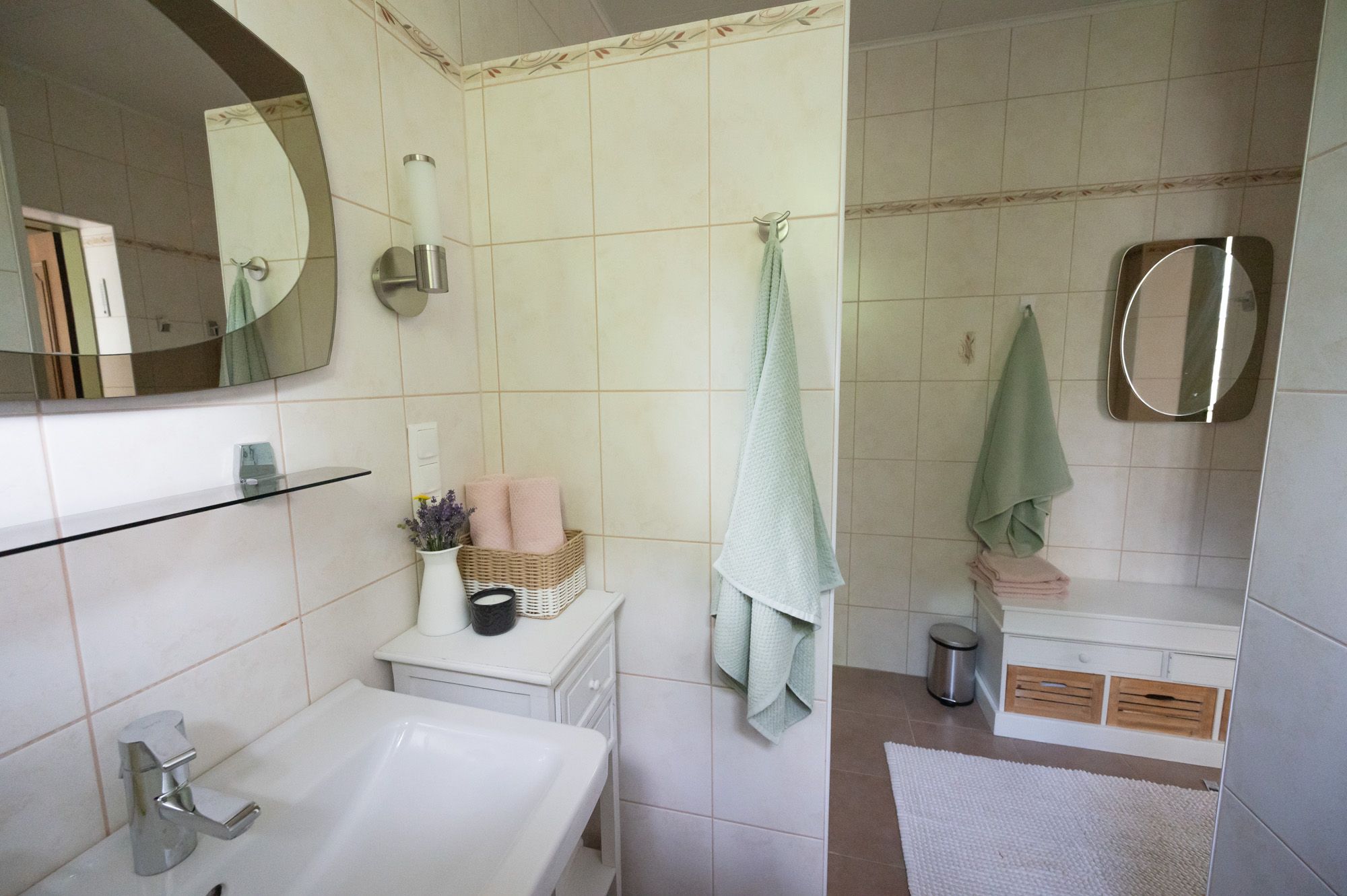 Modern bathroom with washbasin, mirror, towels and decoration.