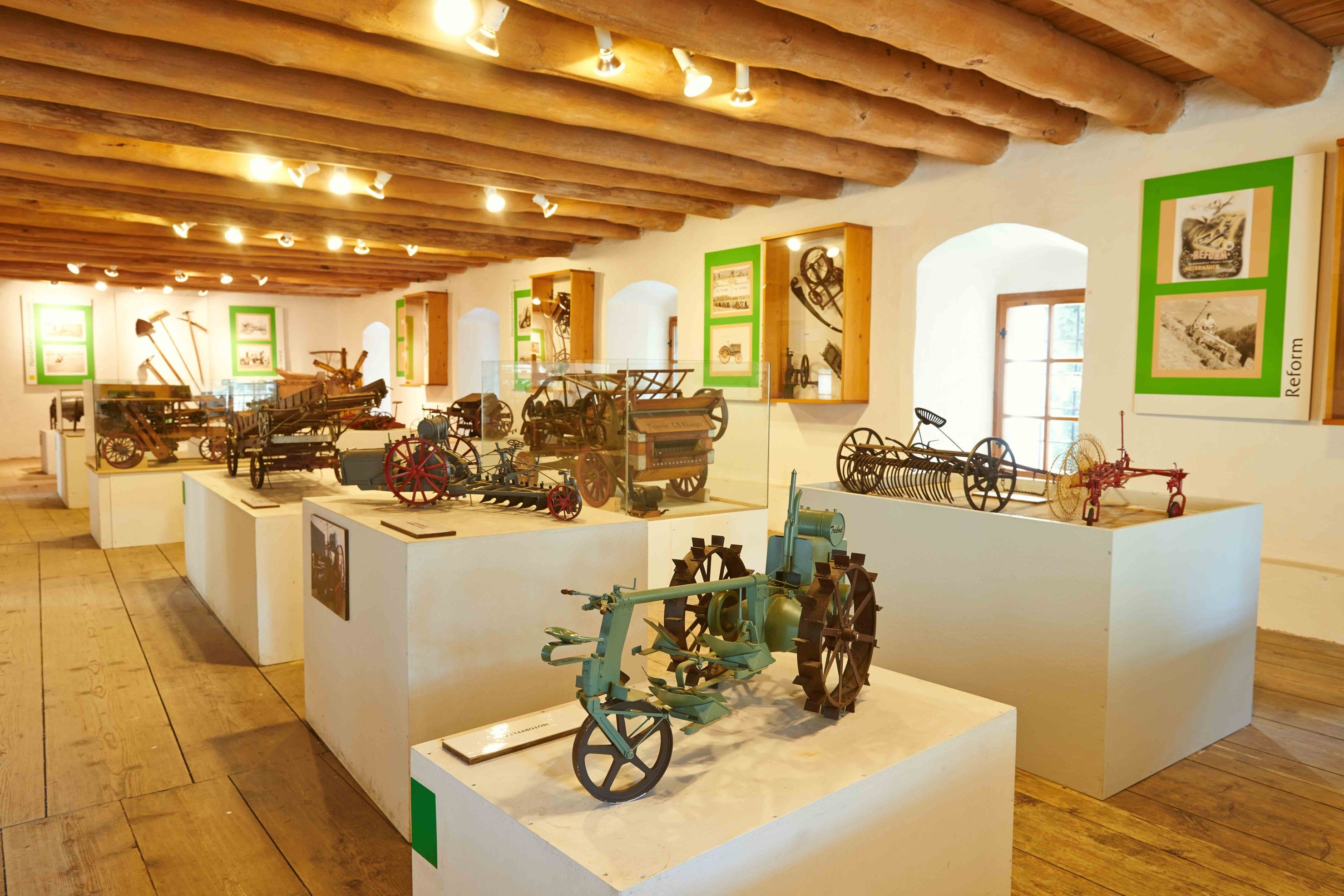 Interior view of the Leiben Agricultural Engineering Museum with historical agricultural equipment on pedestals.
