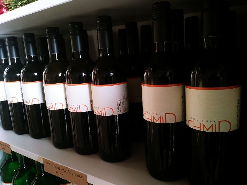 Wine bottles with the label 'Biohof Schmid' on a shelf.