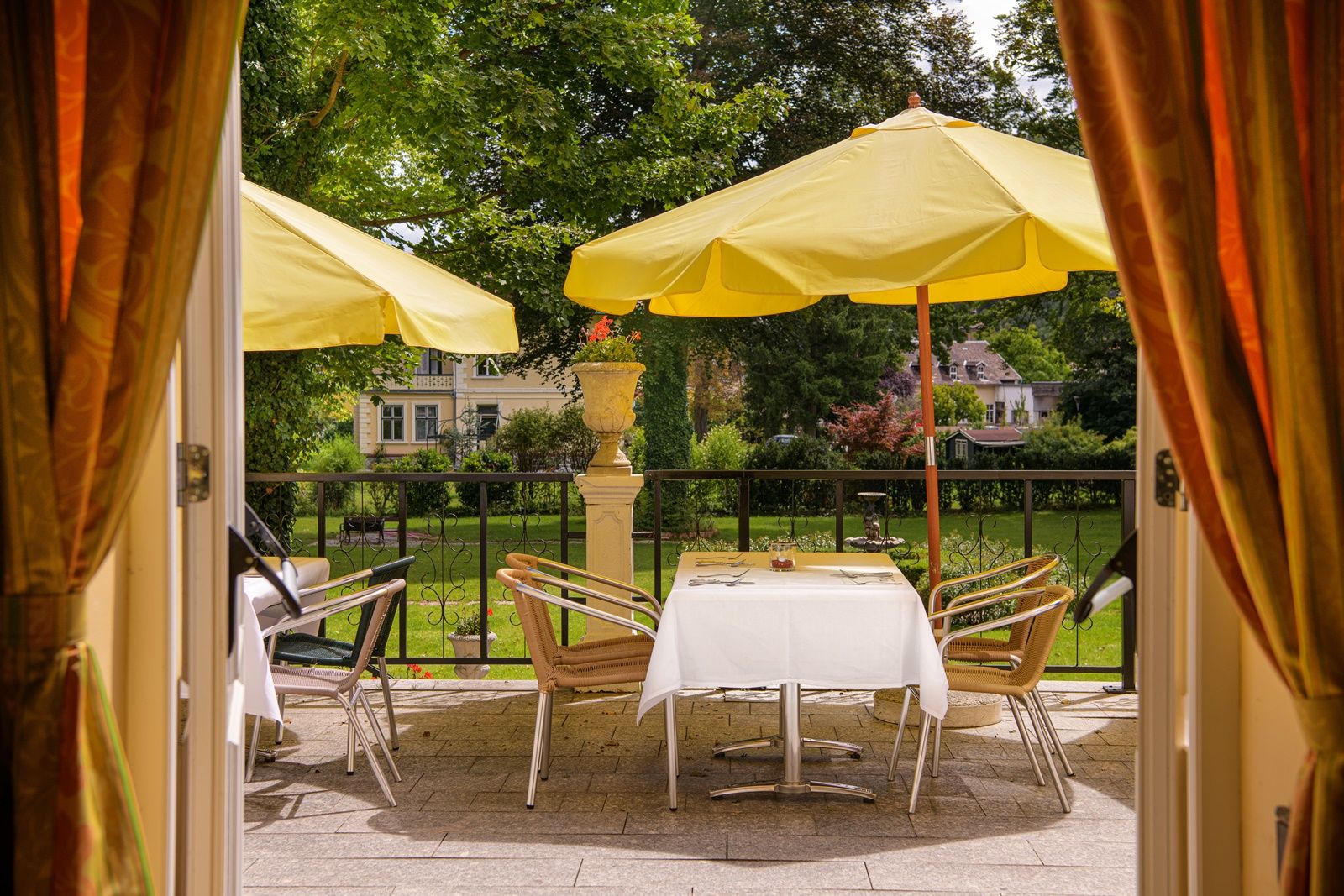 View of a terrace with yellow parasols and a laid table, surrounded by green countryside.