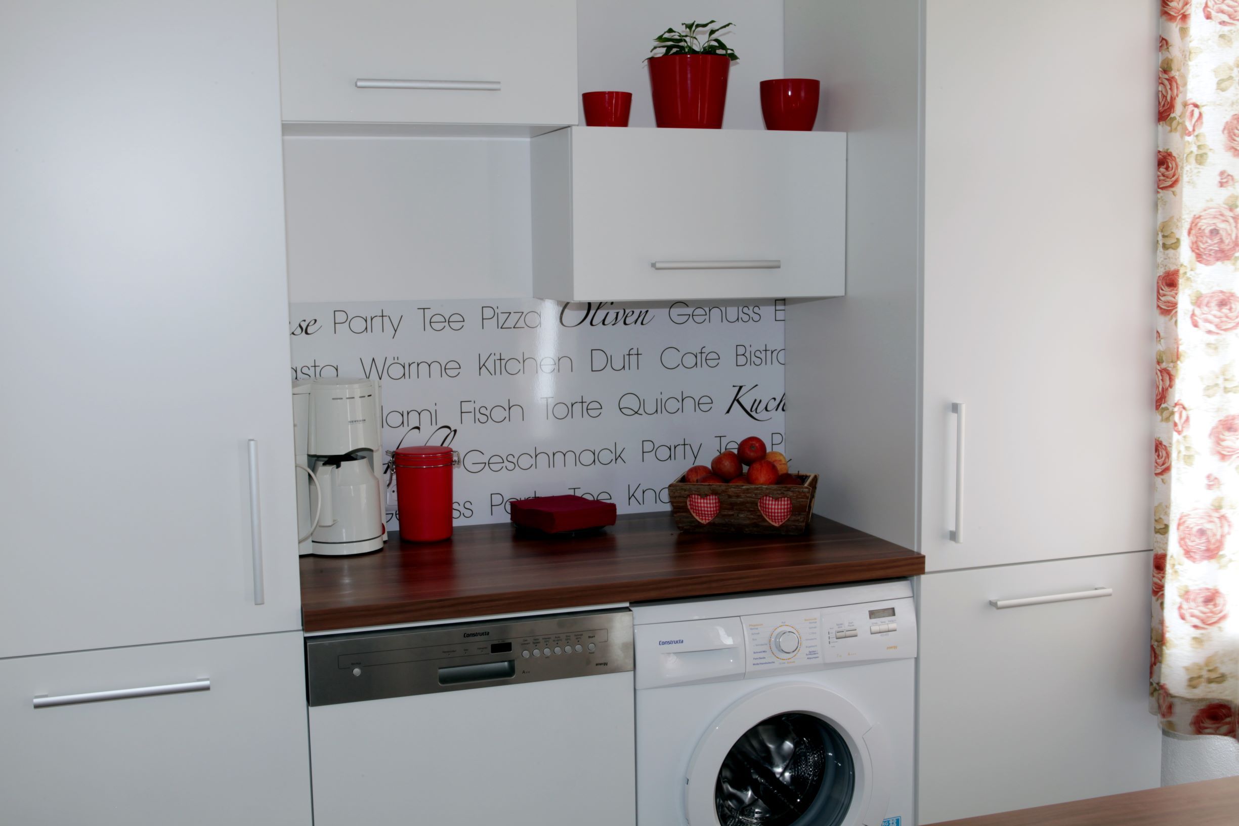 Kitchenette with washing machine, dishwasher, coffee machine and decoration.
