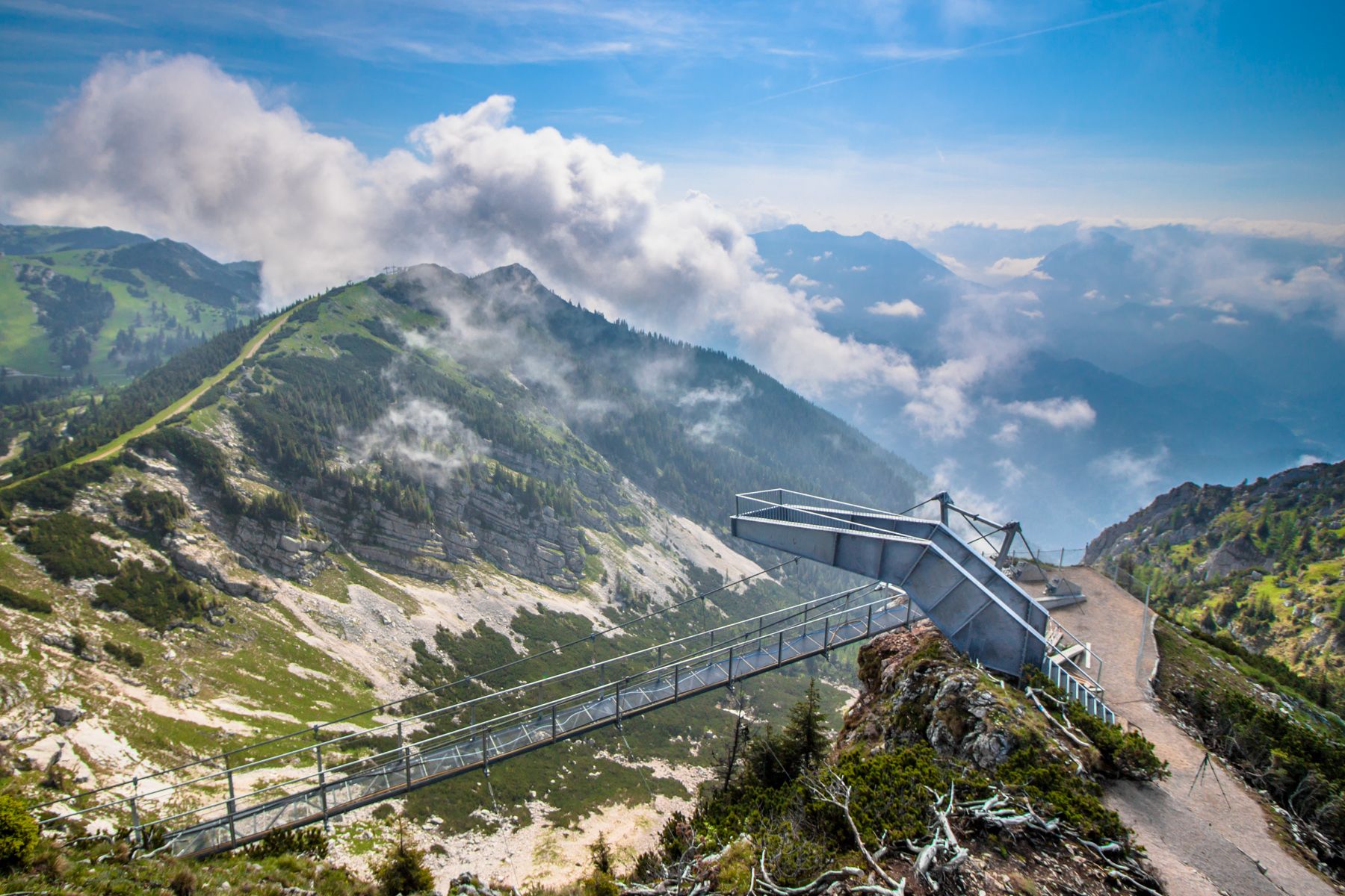 Viewing platform on a mountain with clouds and green landscape.