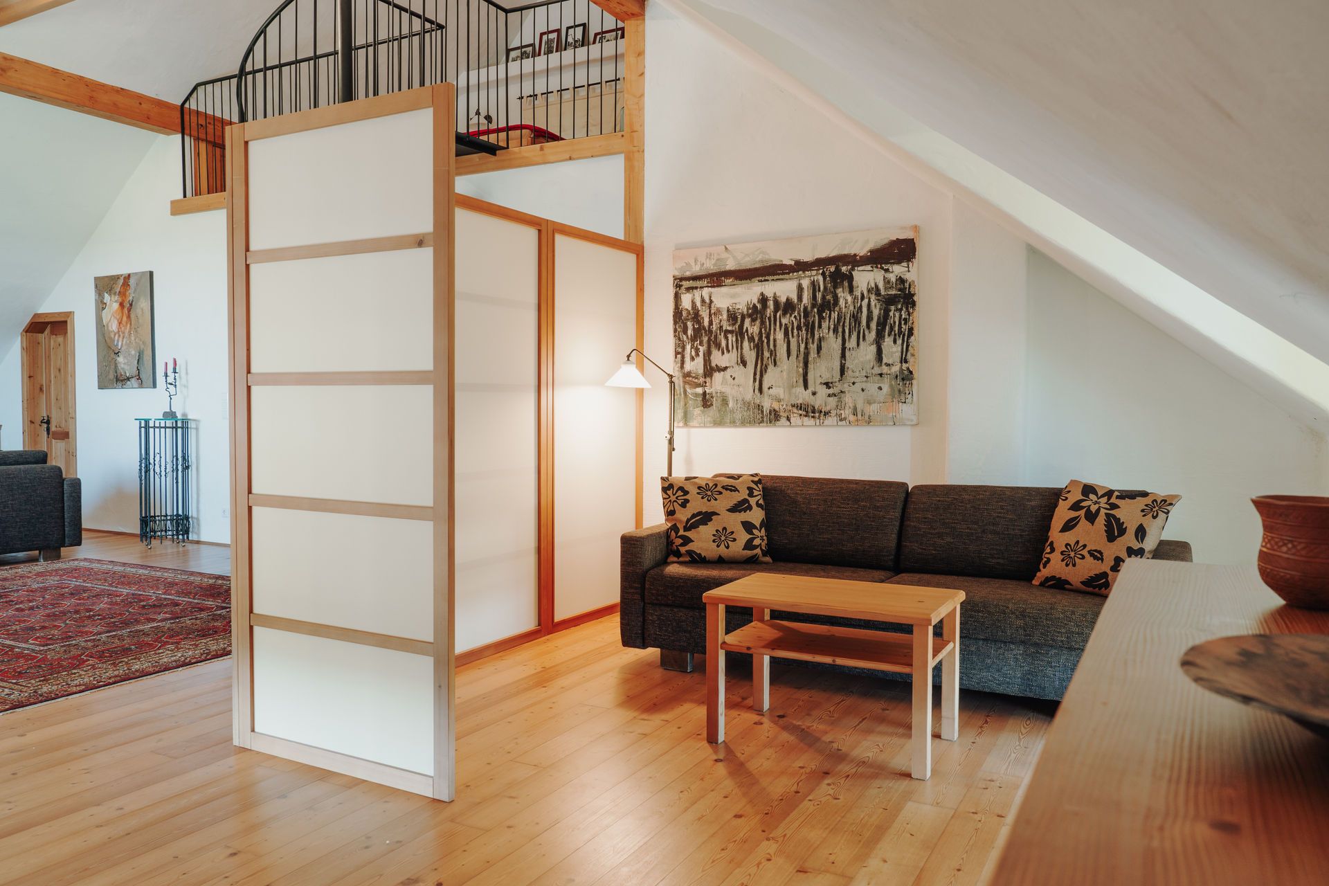 Cozy sitting area with sofa, coffee table and room divider in an attic room.