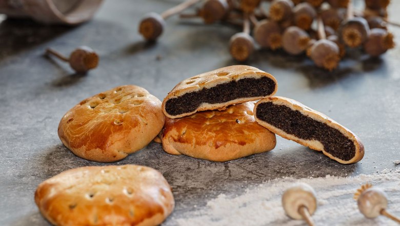 Poppy seed cookies on a table with poppy seed capsules in the background.