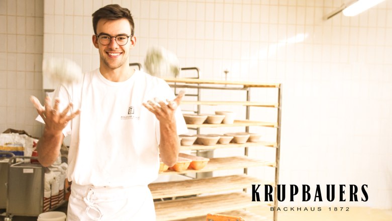 A baker juggles with balls of dough in a bakery.