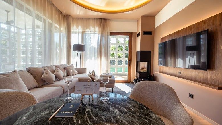 Modern living room with sofa, large TV and glass table.