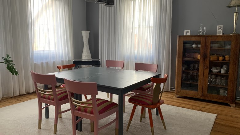 Dining room with table, six chairs, display cabinet and curtains.
