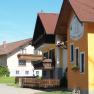 Waldviertel children's farm building with yellow fa&ccedil;ade and wooden balconies, surrounded by green countryside.