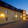Yellow hotel building at dusk with illuminated windows and entrance.