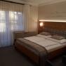 Cozy bedroom with double bed, wooden wall and curtains.
