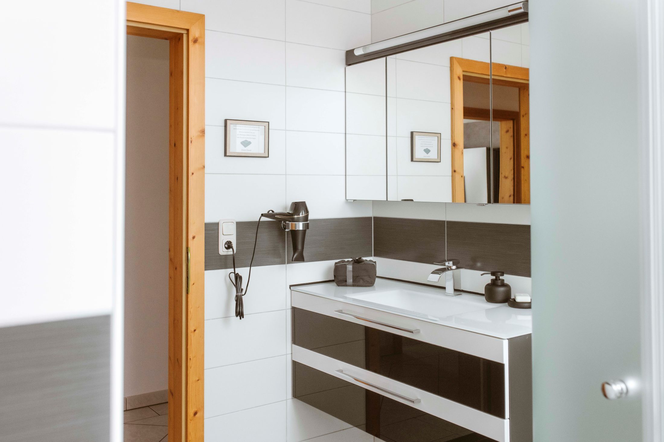 Modern bathroom with mirror, washbasin and hairdryer on the wall.