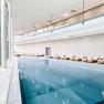 Interior view of a modern spa area with pool and loungers.