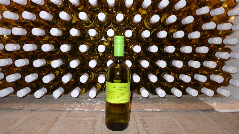 A bottle of Gr&uuml;ne Veltliner in front of a shelf full of wine bottles.