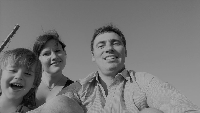 Black and white photo of a smiling family consisting of a man, a woman and a child looking into the camera.