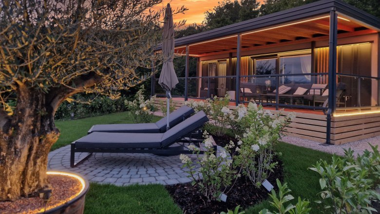 Johannesbachklamm Chalet, © Johannesbachklamm Chalet A modern chalet with terrace and sun loungers in the garden at sunset.