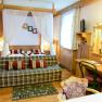 Cozy hotel room with double bed, sofa, desk and mirror in rustic style.