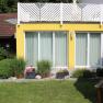 Yellow garden apartment with large windows and well-kept garden.