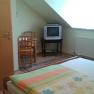 A simply furnished room with a bed, TV and table under a sloping roof.
