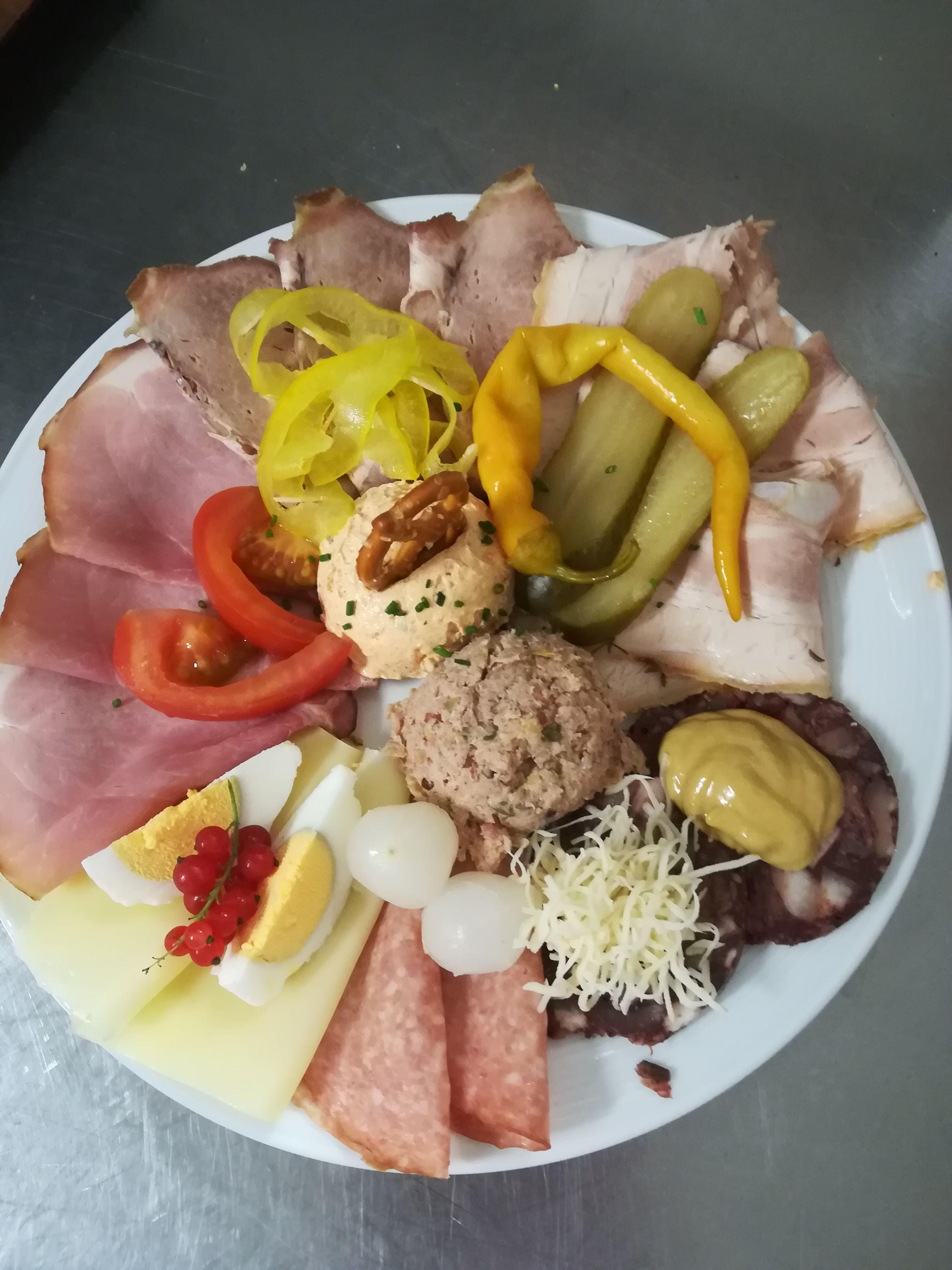 A plate with various types of sausage and cheese, eggs, onions, peppers and spreads.