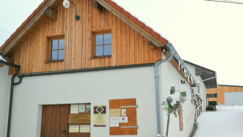 A traditional building with wooden cladding and signs on the wall, surrounded by snow.