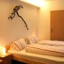 Cozy bedroom with double bed, bedside lamp and grapevine decoration on the wall.
