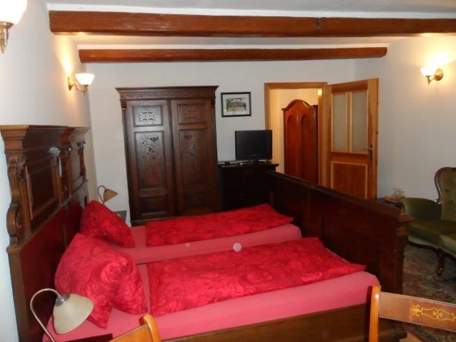 A traditionally furnished double room with two single beds, a wooden wardrobe and a small TV.