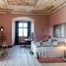Elegant bedroom with antique ceiling, pink walls and wooden floor.